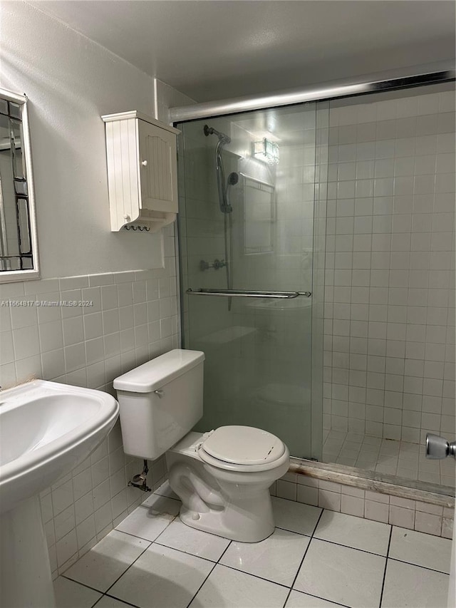 bathroom with tile patterned flooring, toilet, a shower with door, and tile walls