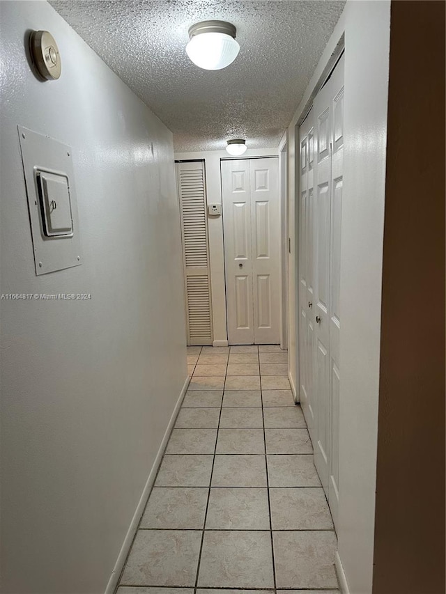 hall featuring light tile patterned floors and a textured ceiling