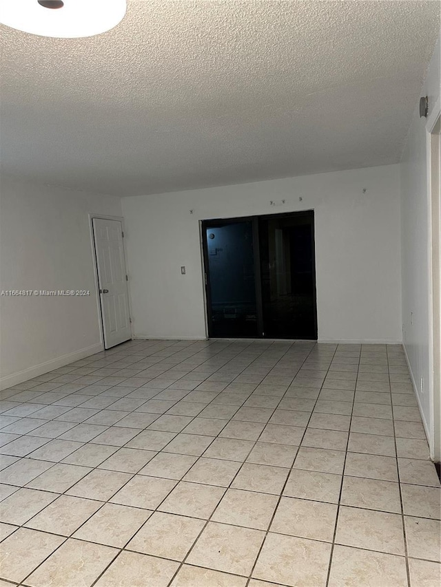 unfurnished room with a textured ceiling and light tile patterned flooring