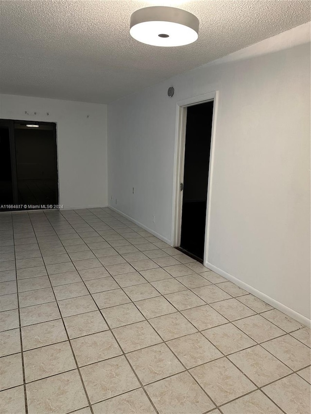 tiled spare room with a textured ceiling