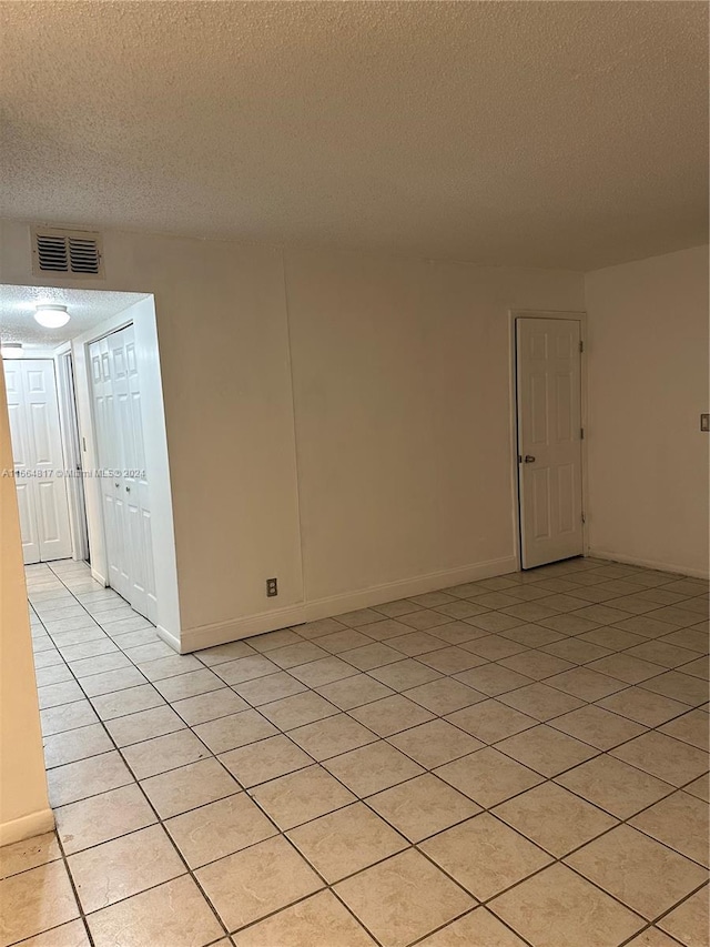 tiled spare room with a textured ceiling