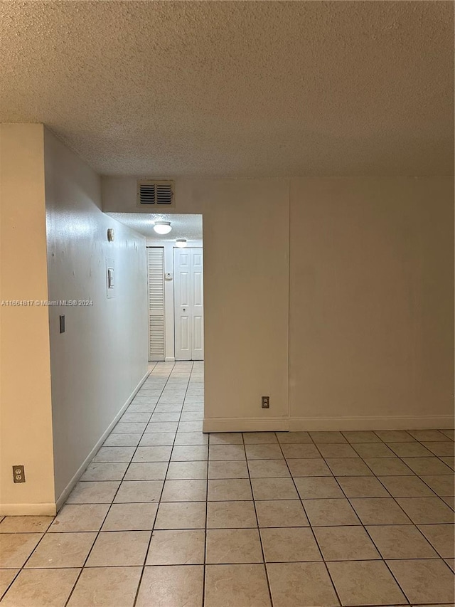 tiled empty room featuring a textured ceiling