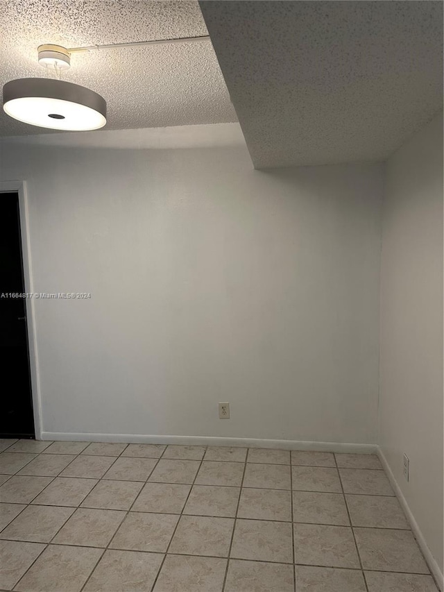 tiled spare room featuring a textured ceiling