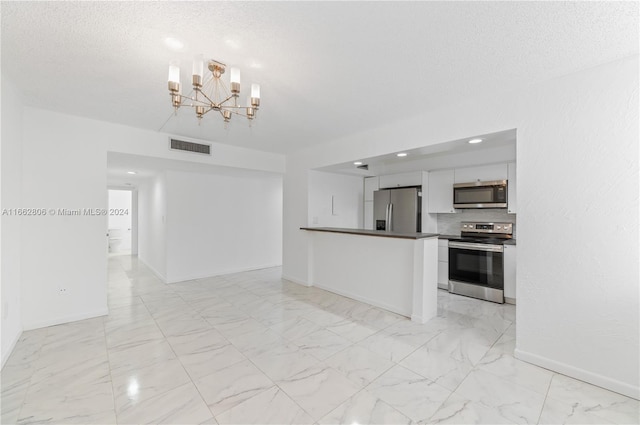 kitchen featuring a textured ceiling, a chandelier, stainless steel appliances, and white cabinets