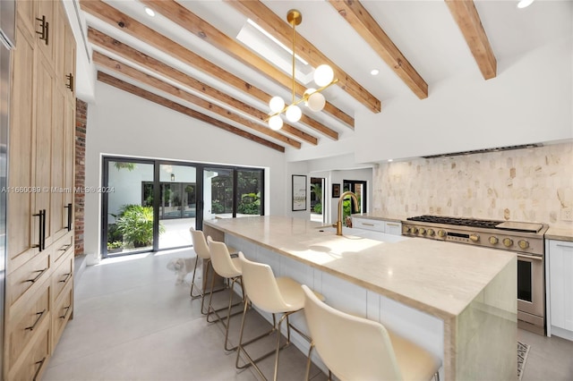 kitchen featuring vaulted ceiling with beams, a center island with sink, high end stainless steel range oven, and a breakfast bar