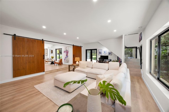 living room featuring a barn door, light hardwood / wood-style floors, and a wealth of natural light