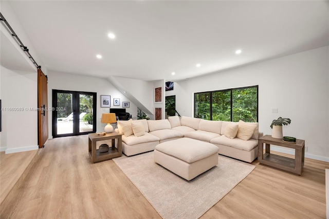 living room featuring a barn door, light hardwood / wood-style floors, and french doors