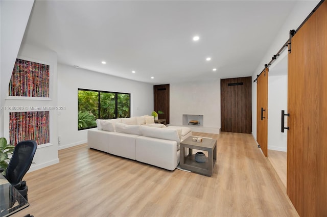 living room with a barn door and light hardwood / wood-style flooring