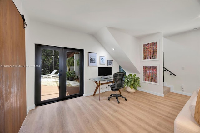 home office featuring a barn door, light hardwood / wood-style flooring, and french doors