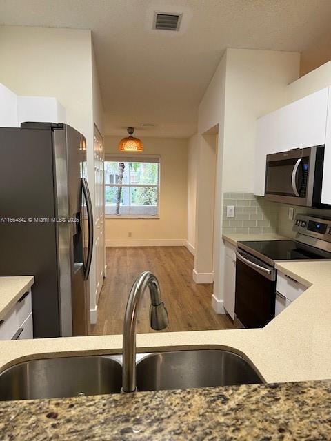 kitchen featuring sink, appliances with stainless steel finishes, tasteful backsplash, white cabinets, and dark hardwood / wood-style flooring