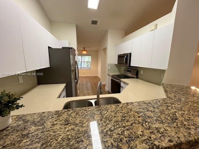 kitchen with stainless steel appliances, sink, white cabinets, and backsplash