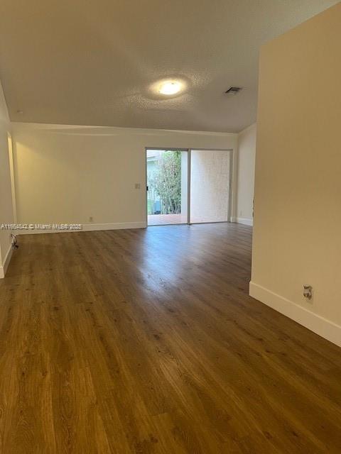 empty room with dark hardwood / wood-style floors and a textured ceiling