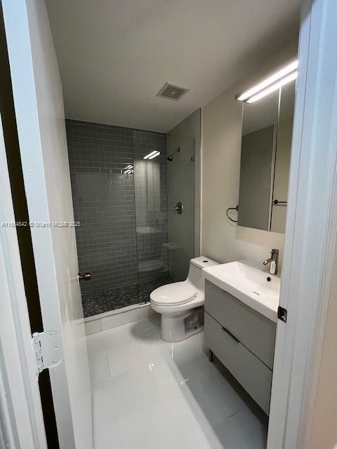 bathroom with vanity, tile patterned floors, toilet, and tiled shower