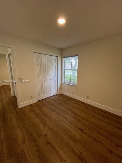 unfurnished bedroom featuring dark wood-type flooring and a closet