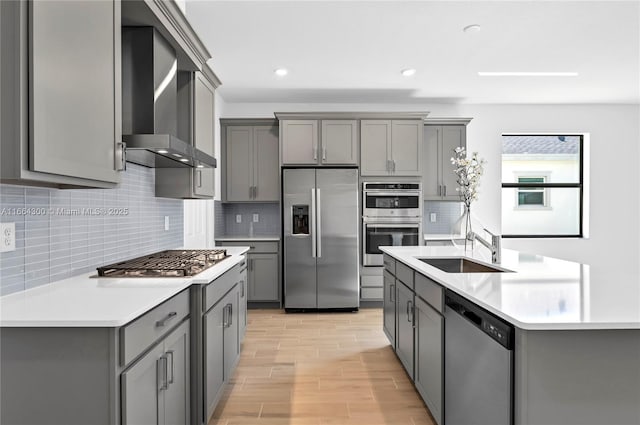 kitchen featuring wall chimney exhaust hood, stainless steel appliances, and gray cabinetry