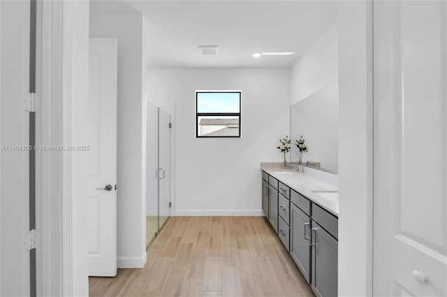 bathroom with vanity, a shower with shower door, and hardwood / wood-style floors