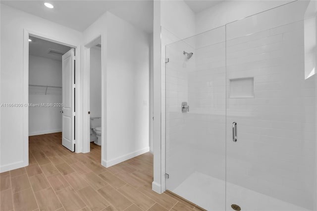 bathroom with wood-type flooring, toilet, and walk in shower