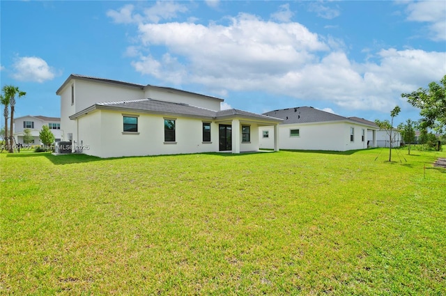 rear view of property with cooling unit and a lawn