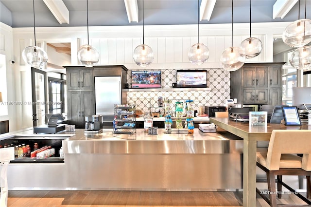 kitchen with beamed ceiling, decorative light fixtures, decorative backsplash, and light wood-type flooring