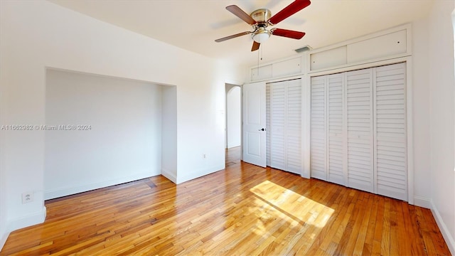 unfurnished bedroom with light hardwood / wood-style floors, two closets, and ceiling fan