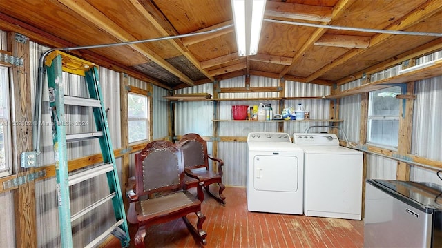 laundry room with wooden walls, light wood-type flooring, and washing machine and dryer