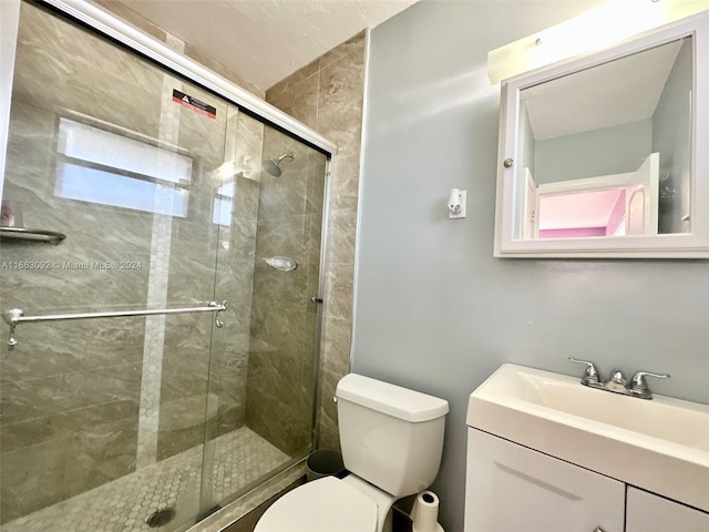 bathroom featuring vanity, toilet, and a shower with shower door