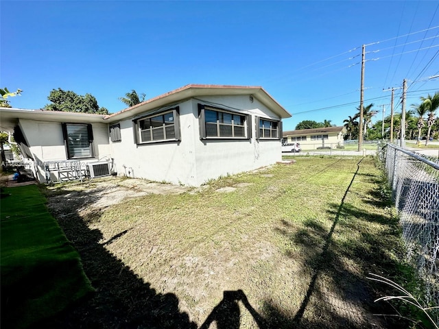 back of house with a lawn and central AC