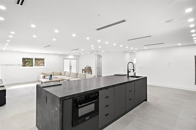 kitchen with black oven, a large island with sink, and sink