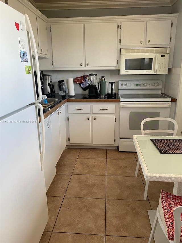 kitchen with light tile patterned flooring, ornamental molding, white appliances, and white cabinetry