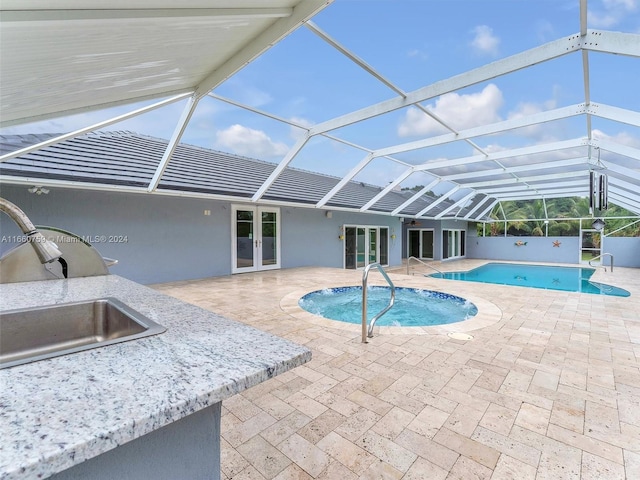 view of swimming pool with a lanai, sink, exterior kitchen, a patio area, and french doors