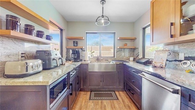 kitchen featuring appliances with stainless steel finishes, backsplash, light stone countertops, and light hardwood / wood-style flooring