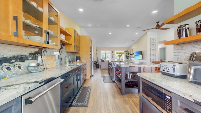 kitchen with light stone countertops, stainless steel appliances, tasteful backsplash, and light hardwood / wood-style flooring