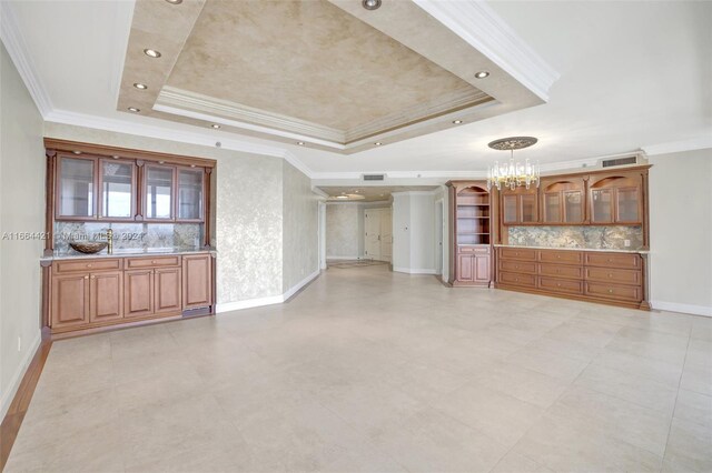 unfurnished living room featuring a notable chandelier, crown molding, and a tray ceiling