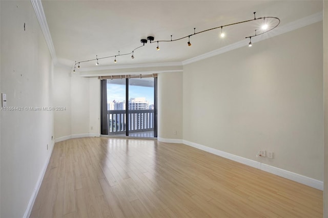 spare room featuring light hardwood / wood-style flooring, rail lighting, and ornamental molding