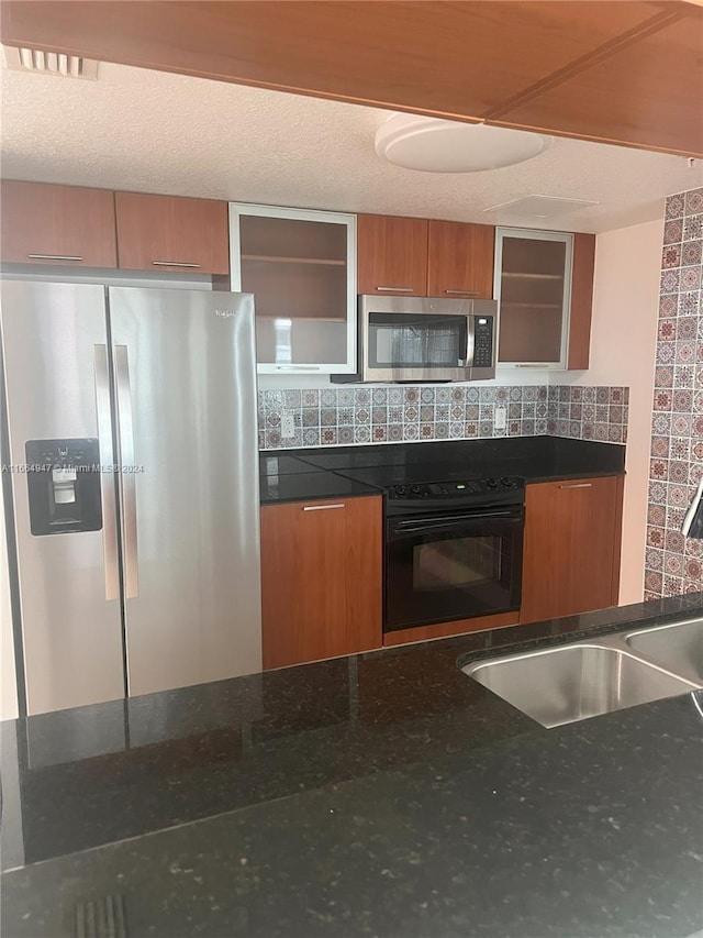 kitchen with dark stone counters, sink, tasteful backsplash, and black appliances