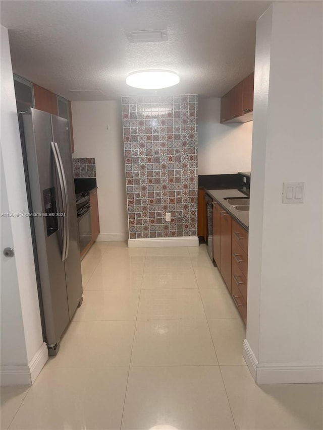 kitchen with a textured ceiling, appliances with stainless steel finishes, sink, and light tile patterned flooring