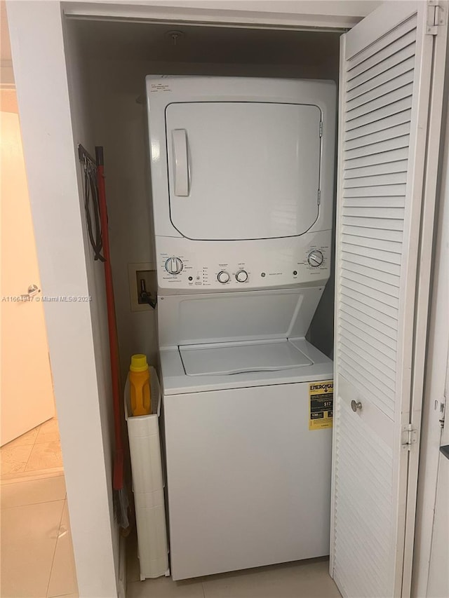 laundry area with stacked washer and clothes dryer and light tile patterned floors