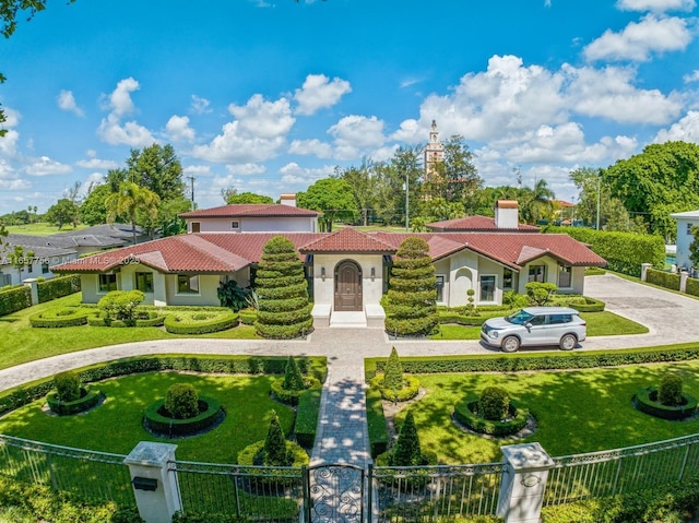 mediterranean / spanish house featuring a fenced front yard, a tile roof, a gate, stucco siding, and a front lawn