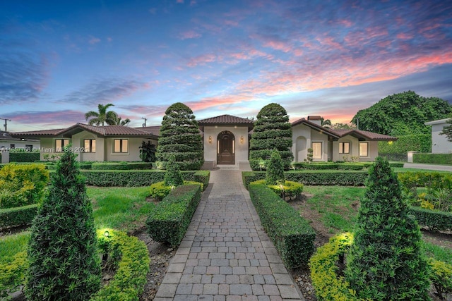 mediterranean / spanish home with a tile roof, decorative driveway, and stucco siding