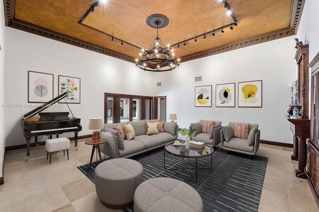 living room featuring track lighting, a chandelier, a high ceiling, and baseboards