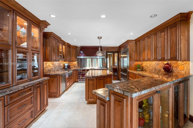 kitchen with brown cabinets, custom range hood, appliances with stainless steel finishes, a kitchen island, and a peninsula