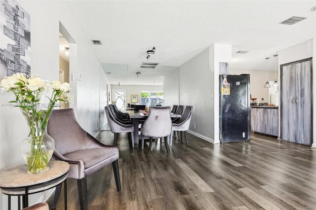 dining room with a textured ceiling and dark wood-type flooring