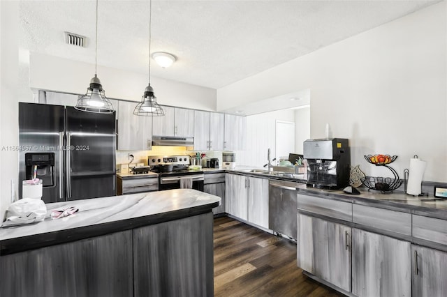 kitchen featuring a textured ceiling, stainless steel appliances, hanging light fixtures, and dark wood-type flooring