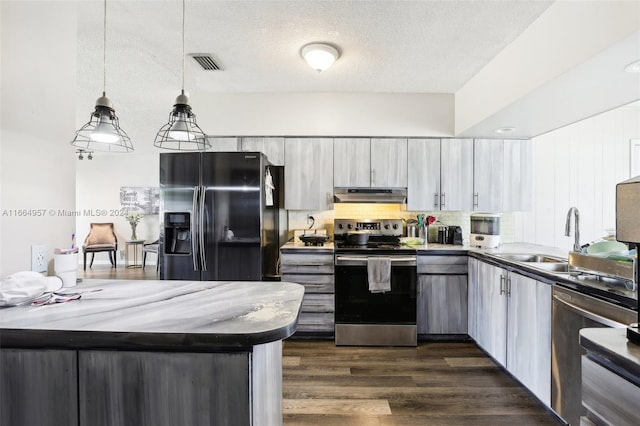 kitchen with hanging light fixtures, sink, tasteful backsplash, dark wood-type flooring, and appliances with stainless steel finishes