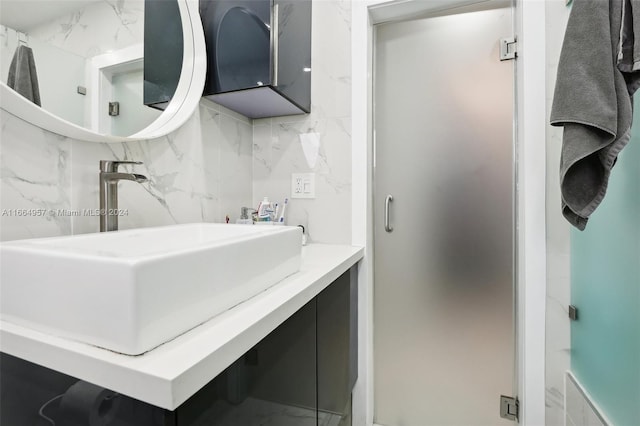 bathroom with decorative backsplash, vanity, and a shower with shower door