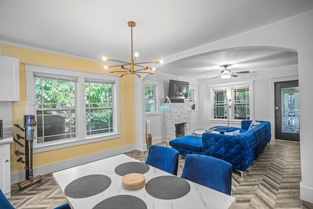 dining space featuring light parquet flooring, ceiling fan with notable chandelier, and ornamental molding