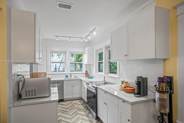 kitchen featuring sink, tasteful backsplash, light parquet flooring, white cabinetry, and appliances with stainless steel finishes