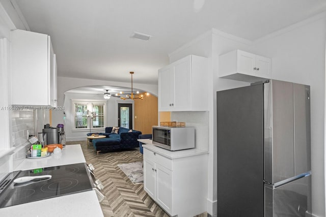 kitchen featuring parquet flooring, white cabinetry, decorative backsplash, appliances with stainless steel finishes, and ornamental molding