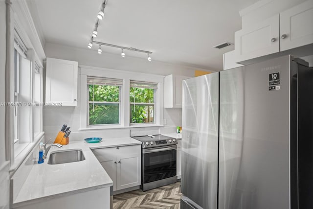 kitchen with white cabinetry, tasteful backsplash, light parquet flooring, stainless steel appliances, and sink