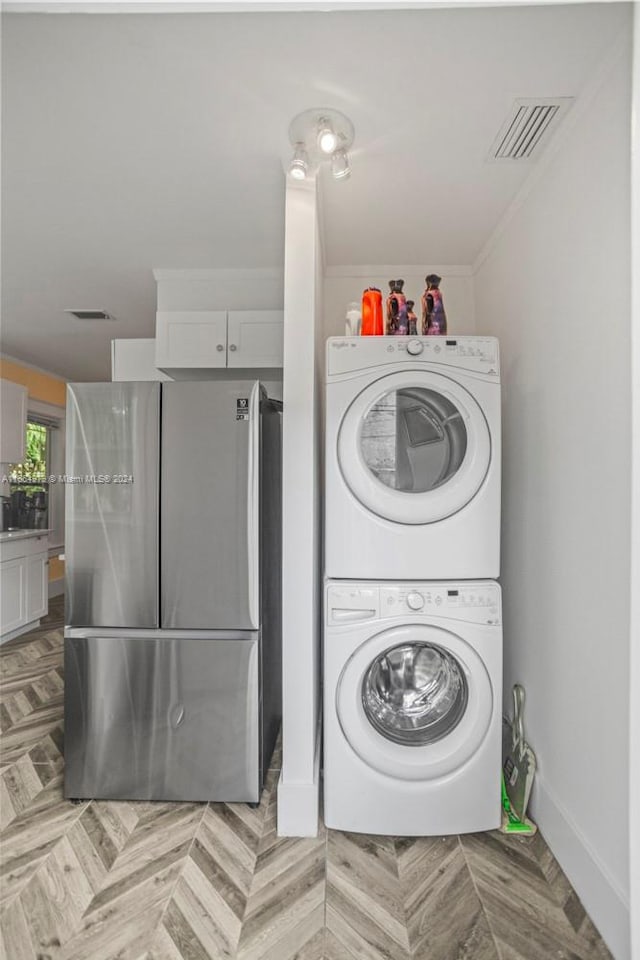 washroom with crown molding, light parquet flooring, and stacked washing maching and dryer